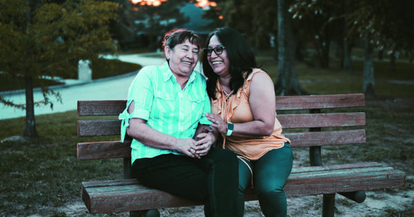 Two Women Sat On Bench Laughing