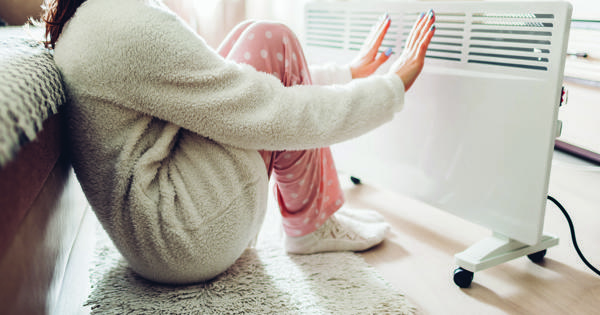 Young Woman In Front Of Storage Heater